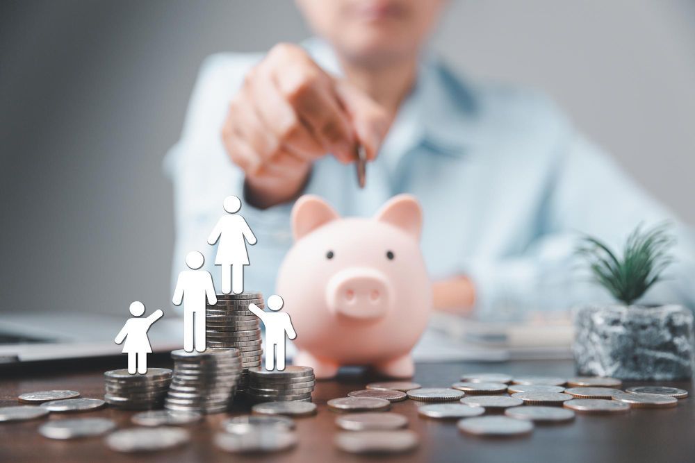 family reaches for each other as man places money in piggy bank with money stacked around family