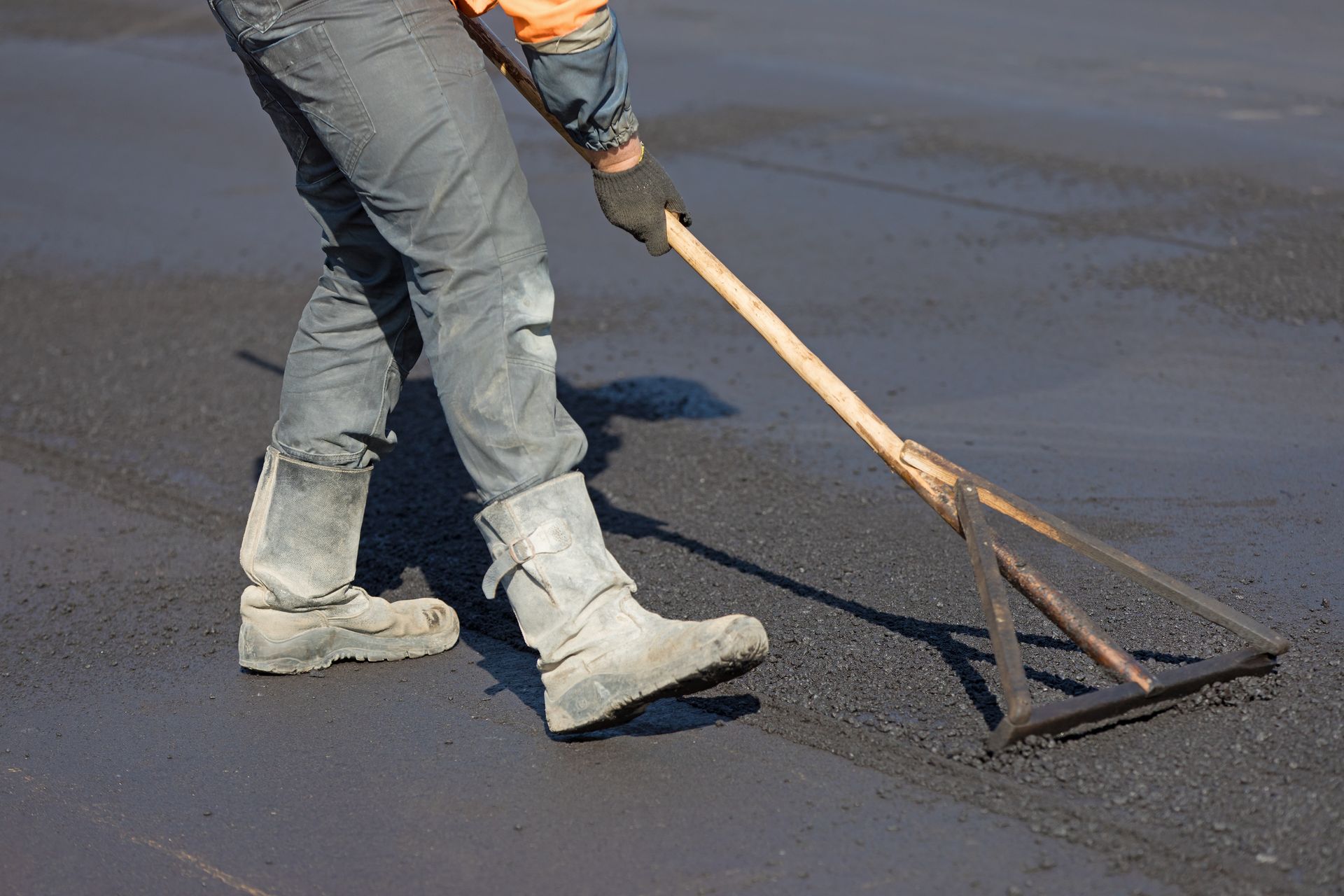 Leveling hot mix asphalt concrete pavement for smooth, flexible surface construction.