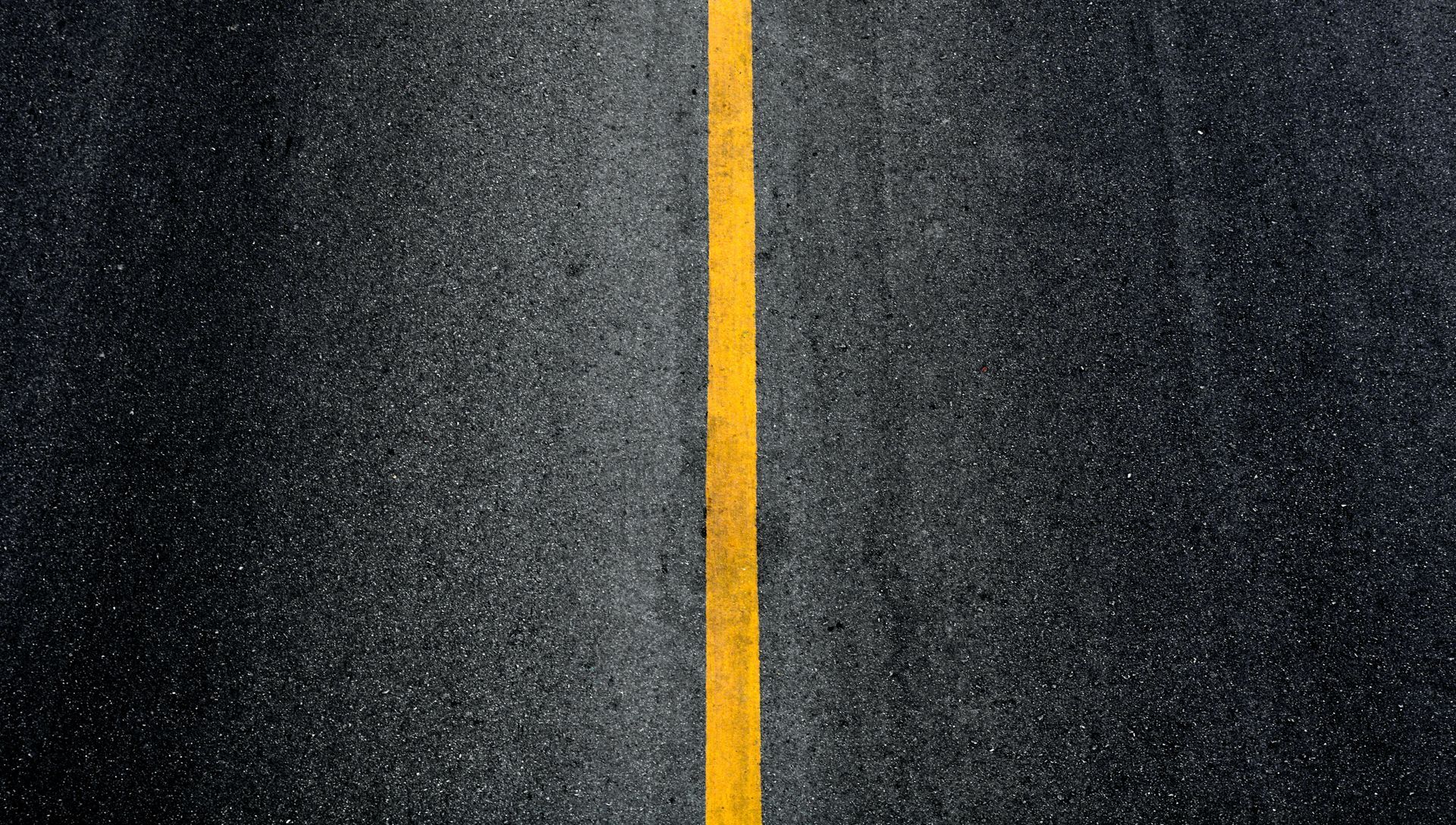 Fresh yellow line marking on asphalt by parking lot asphalt services.