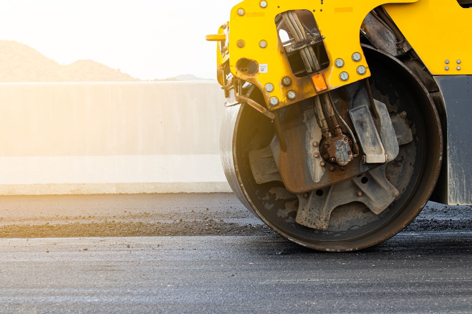Heavy road roller machine delivering expert commercial paving services on a highway job. Heavy road roller machine delivering expert commercial paving services on a highway job.