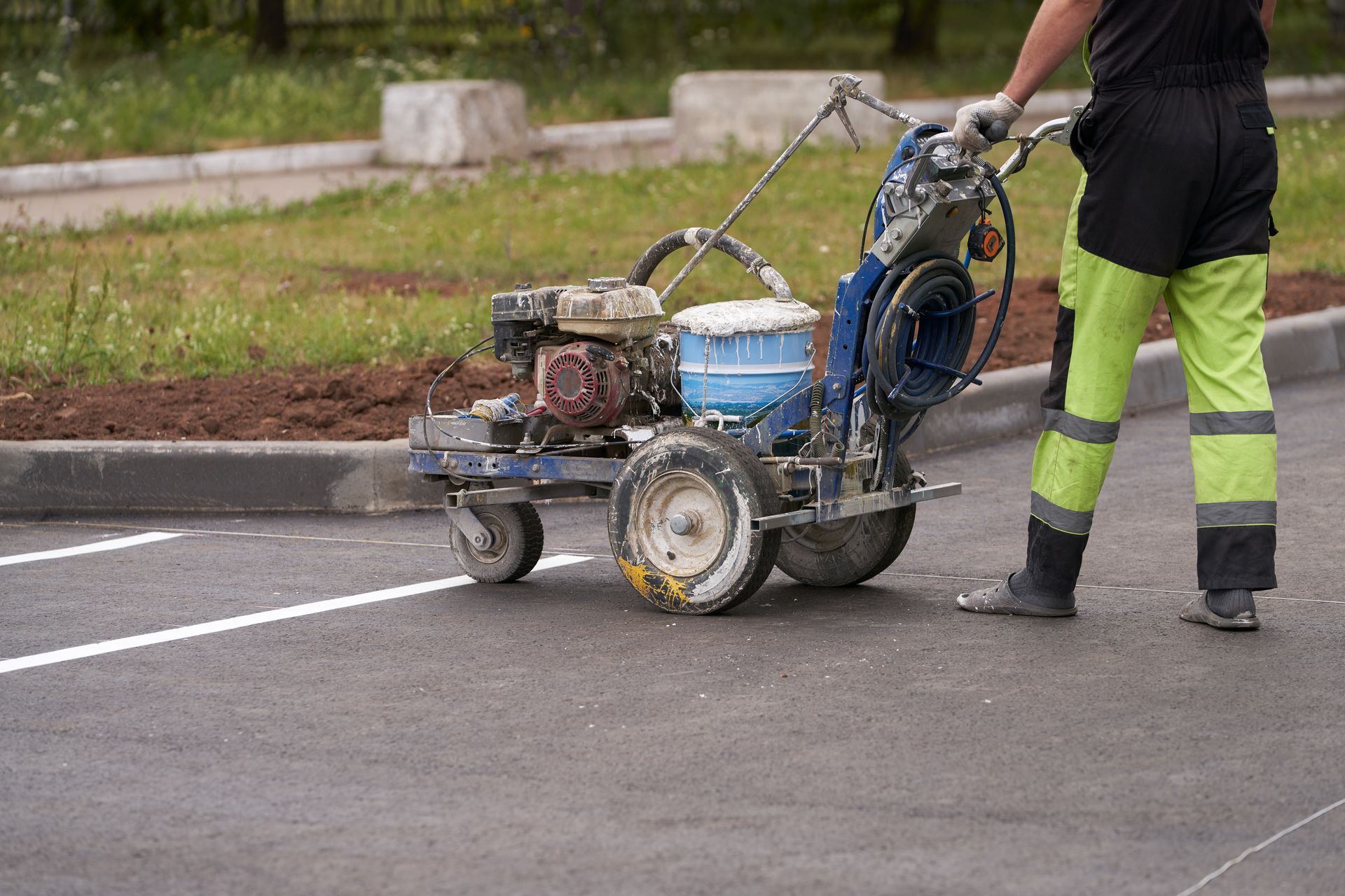 Worker striping fresh asphalt, marking crisp white parking lot lines Worker striping fresh asphalt, marking crisp white parking lot lines