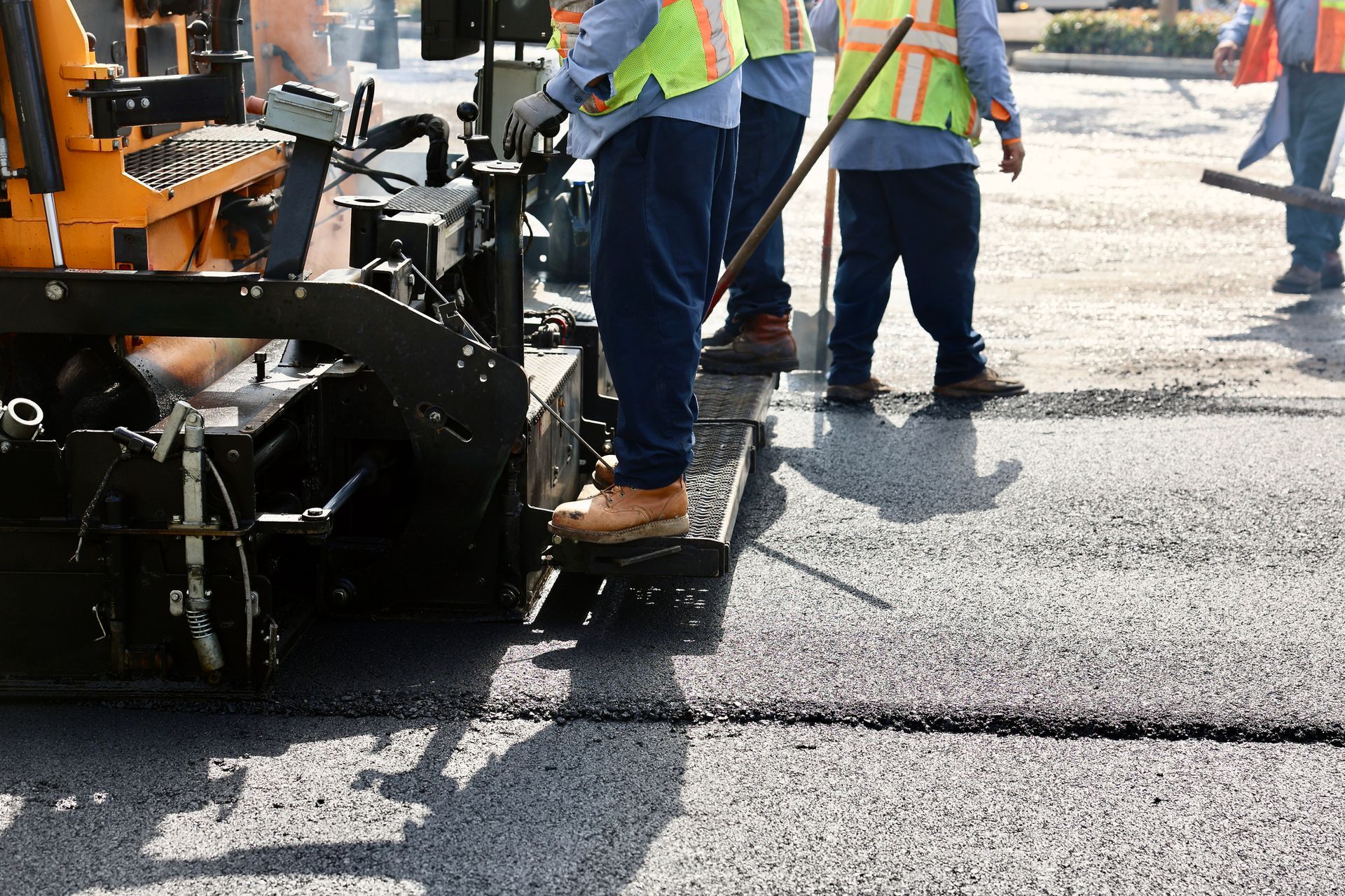 Blue-collar workers operate asphalt pavers. machine | asphalt paving solutions in Houston, TX