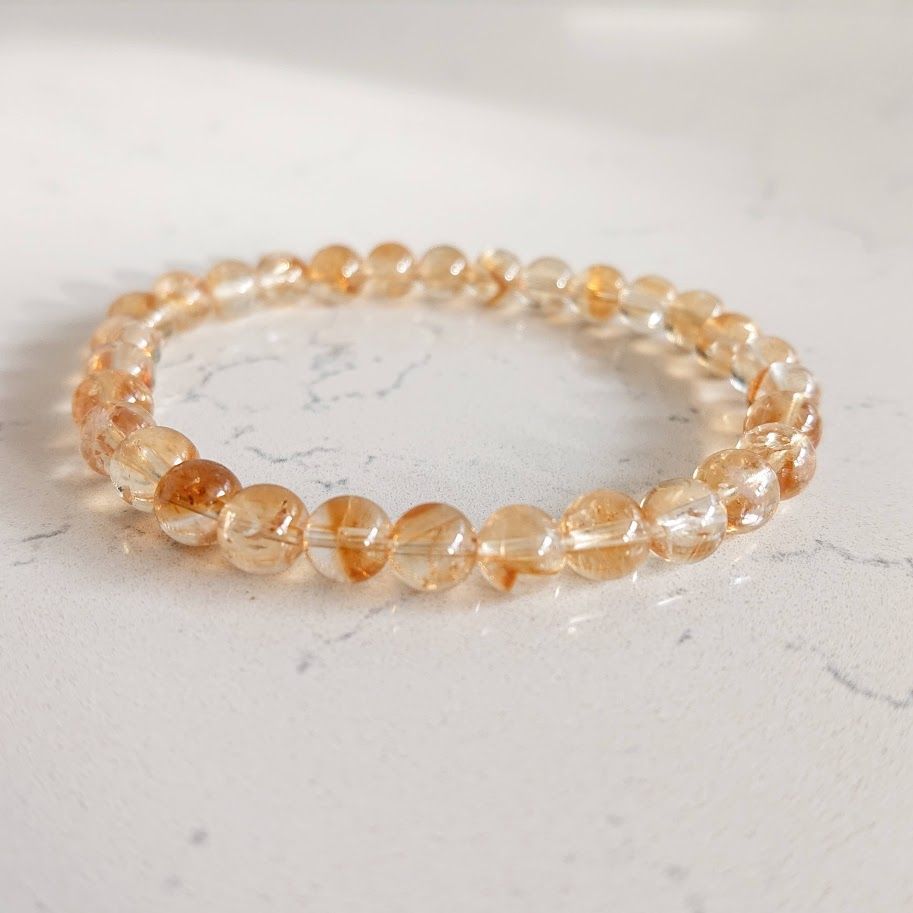 Een close-up van een armband met citrien kralen op een wit oppervlak.