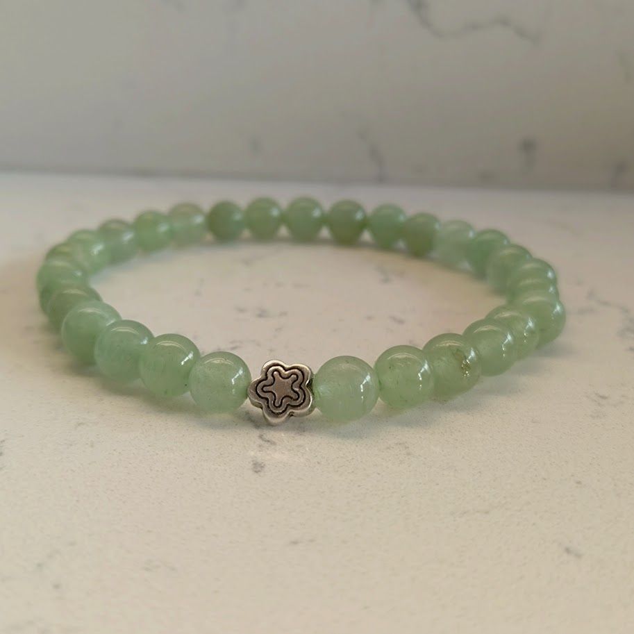 Armband van groene aventurijnkralen op elastiek geregen met een zilverkleur bloemkraal.