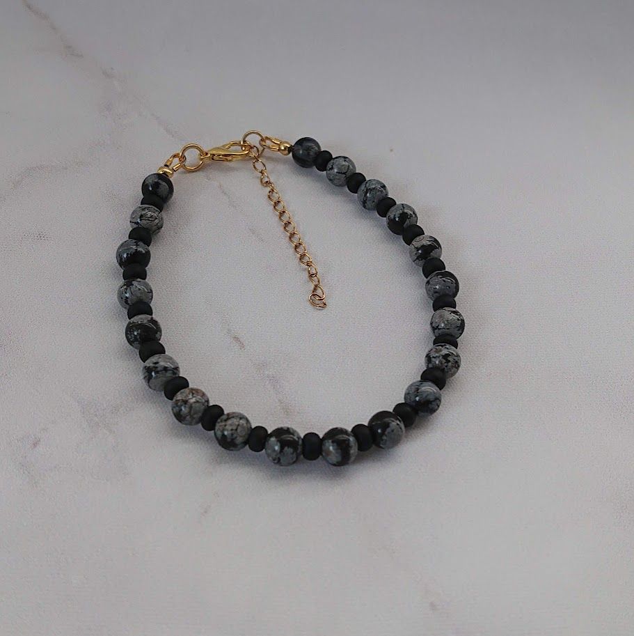 Chique armband van snowflake obsidiaan kralen van 6mm met matzwarte tussenkralen van 4mm en gouden stainless steel sluiting