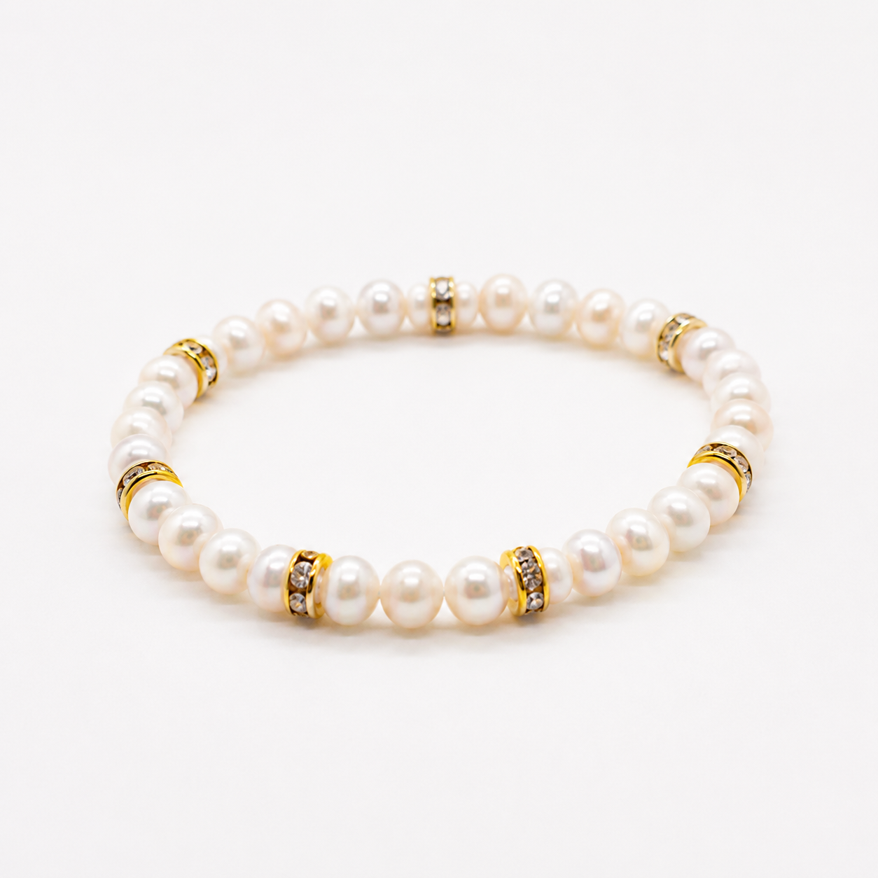 Witte zoetwaterparel armband met gouden strass rondellen op witte achtergrond