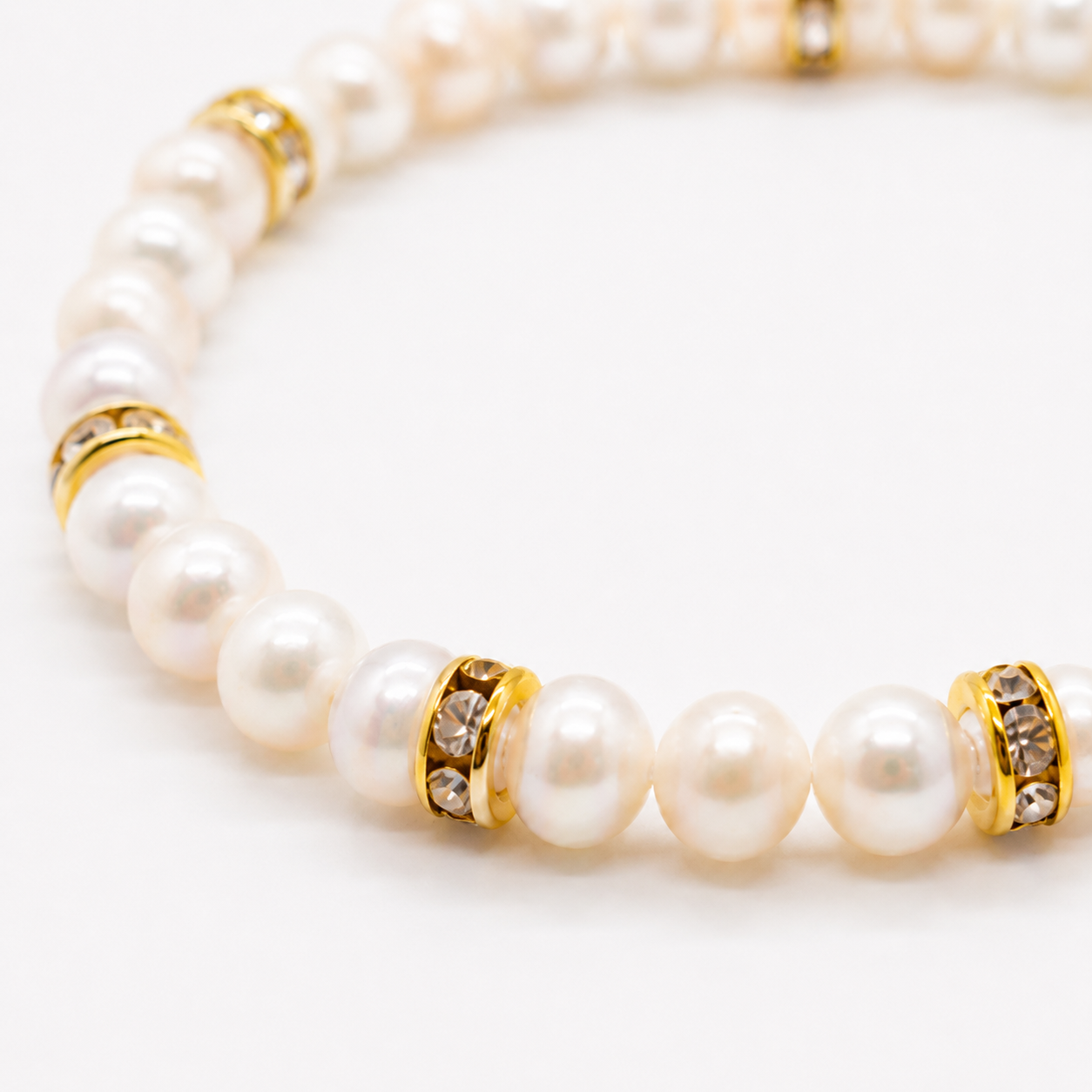 Witte zoetwaterparel armband met gouden strass rondellen op witte achtergrond
