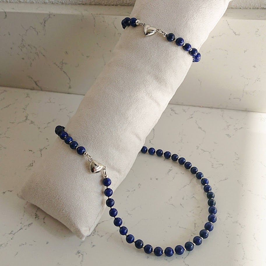 Sieradenset met lapis lazuli kralen en goudkleurige hart magneetsluiting: ketting, armband en oorbellen op witte achtergrond