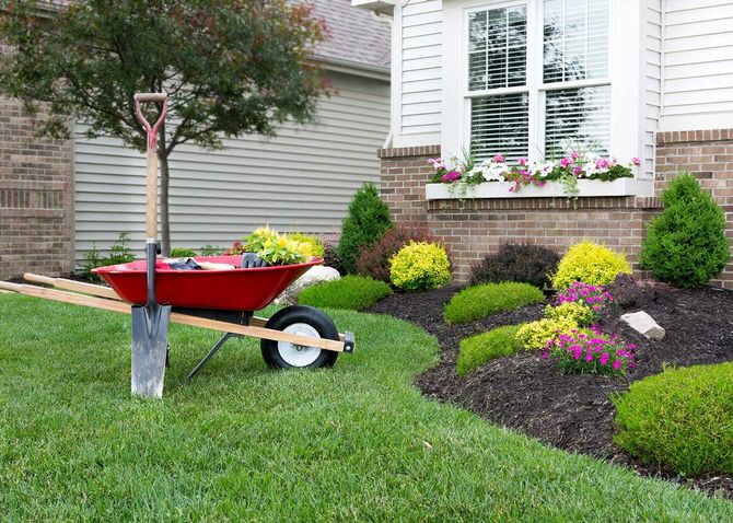 Red wheelbarrow with gardening tools on a lawn Red wheelbarrow with gardening tools on a lawn