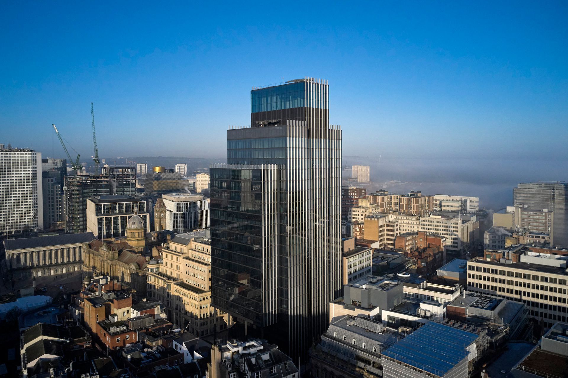 City skyline with a tall glass tower under a clear blue sky