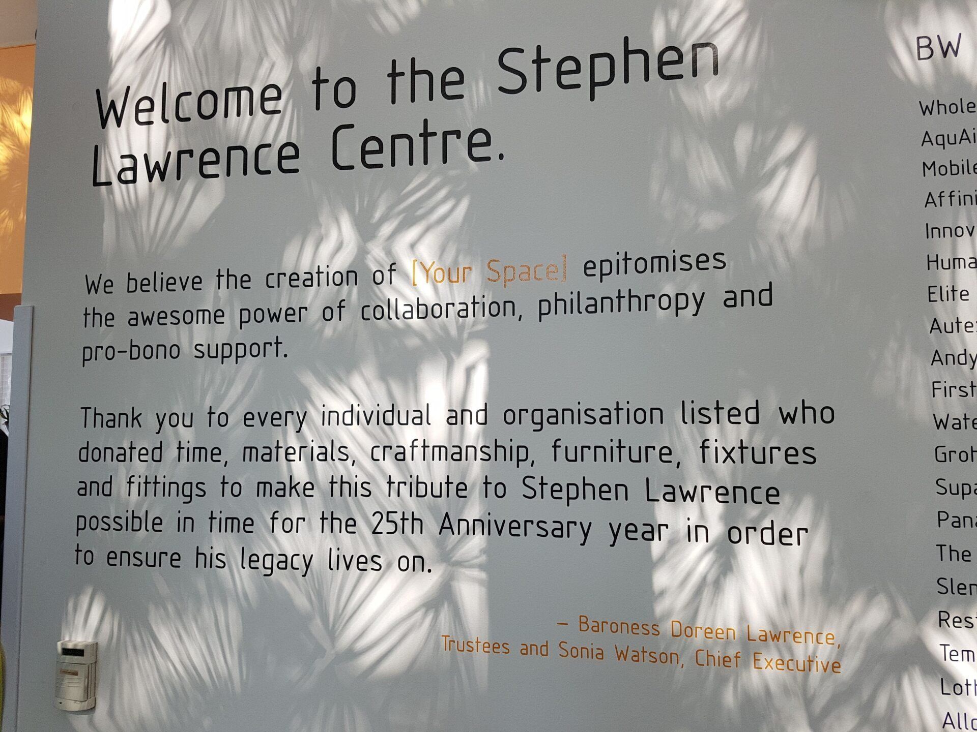 Welcome sign for the Stephen Lawrence Centre with handwritten text on a beige wall.