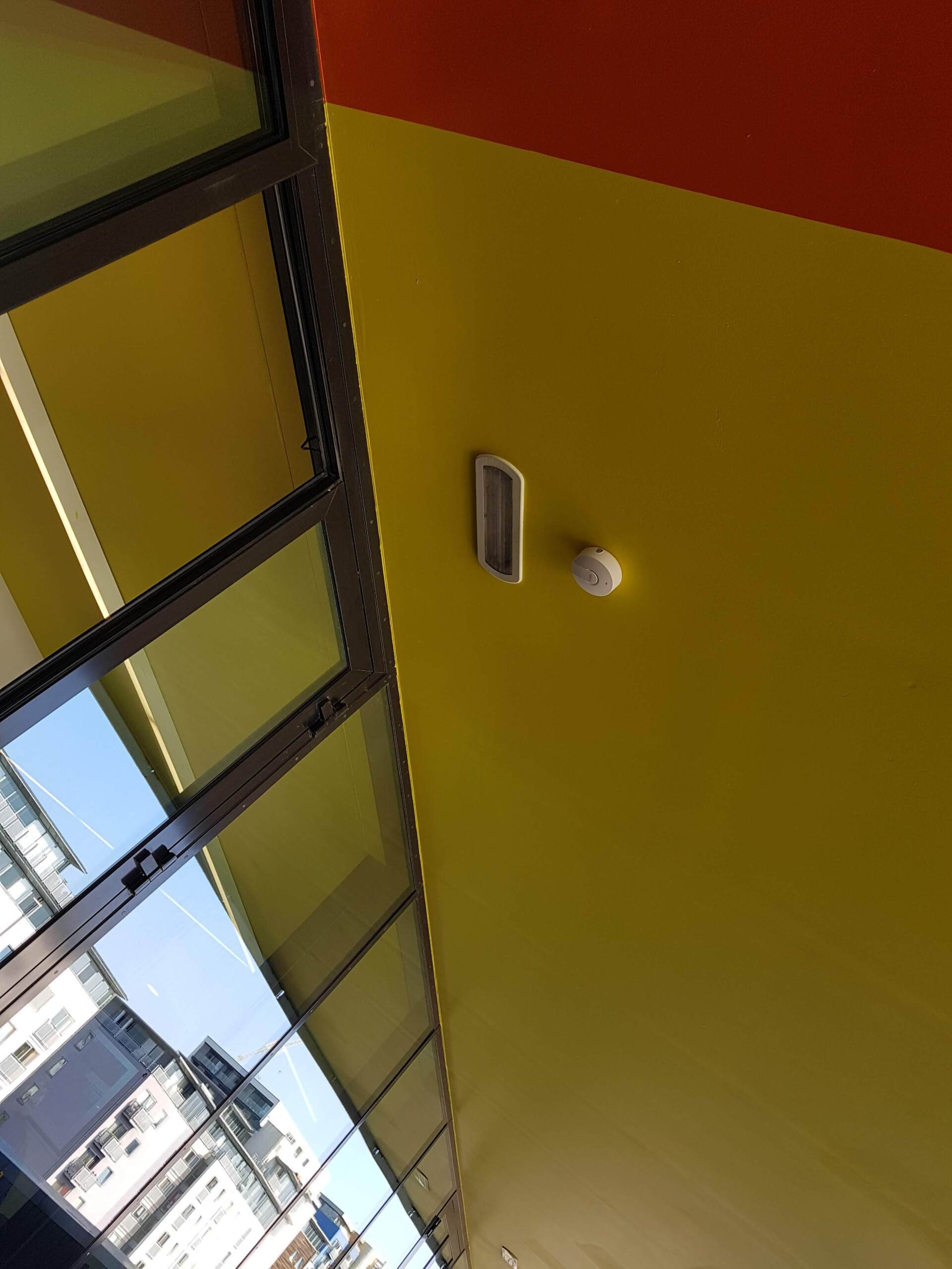 Tilted view of a yellow ceiling with a light fixture and windows along the left side