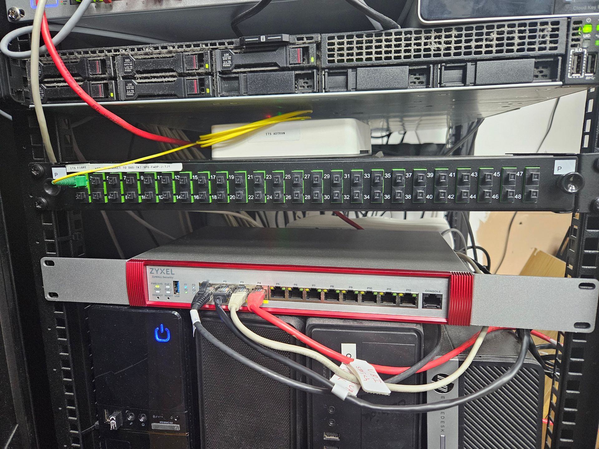 Rack-mounted network equipment with cables and power indicators in a server cabinet