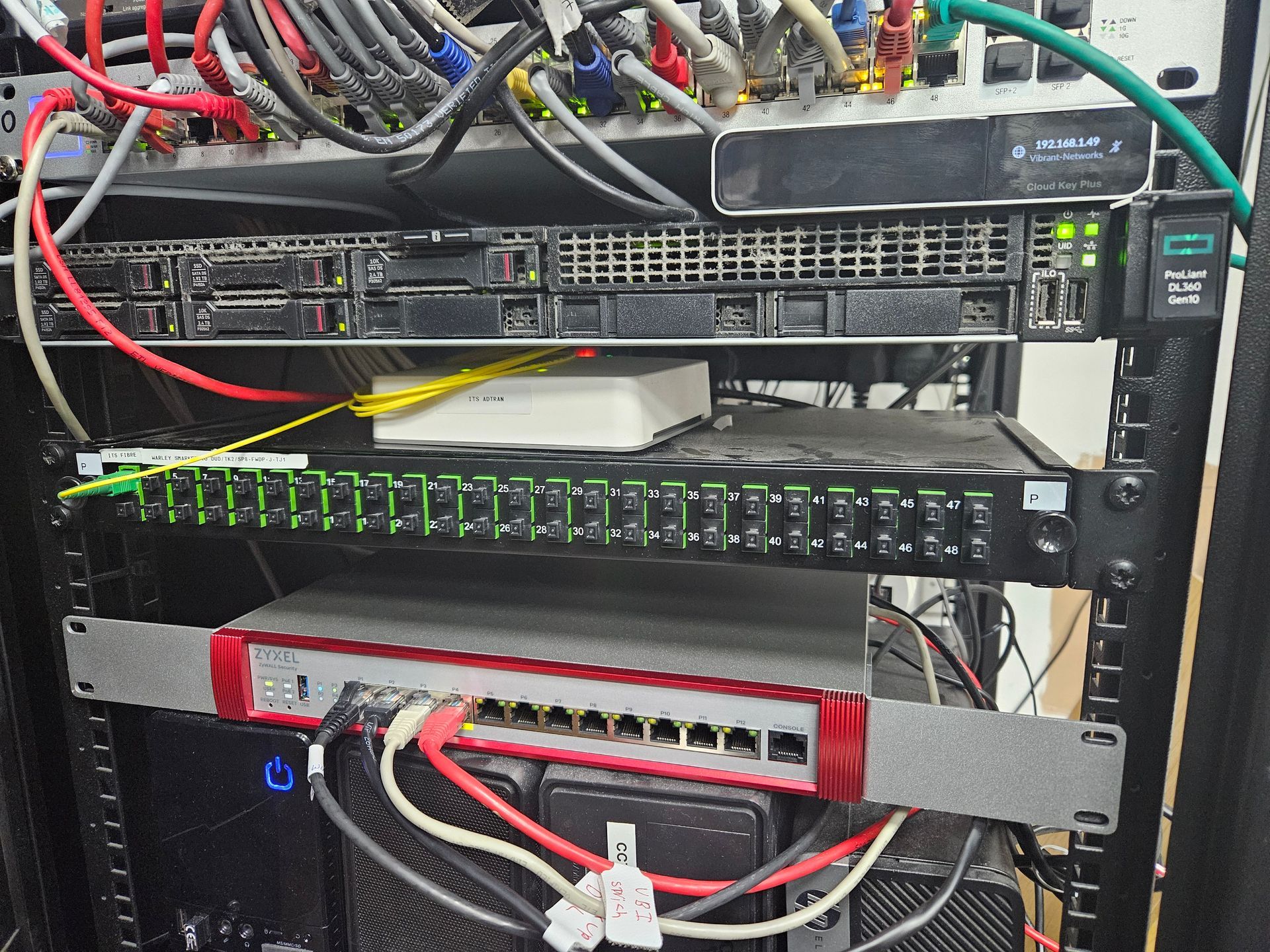 Network rack with stacked servers, switches, and many connected cables in a data center.