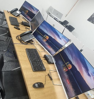 Computer lab with desks, keyboards, mice, and monitors displaying the same sunset wallpaper.