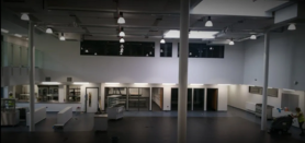 Empty modern gallery interior with white walls, display cases, and ceiling lights