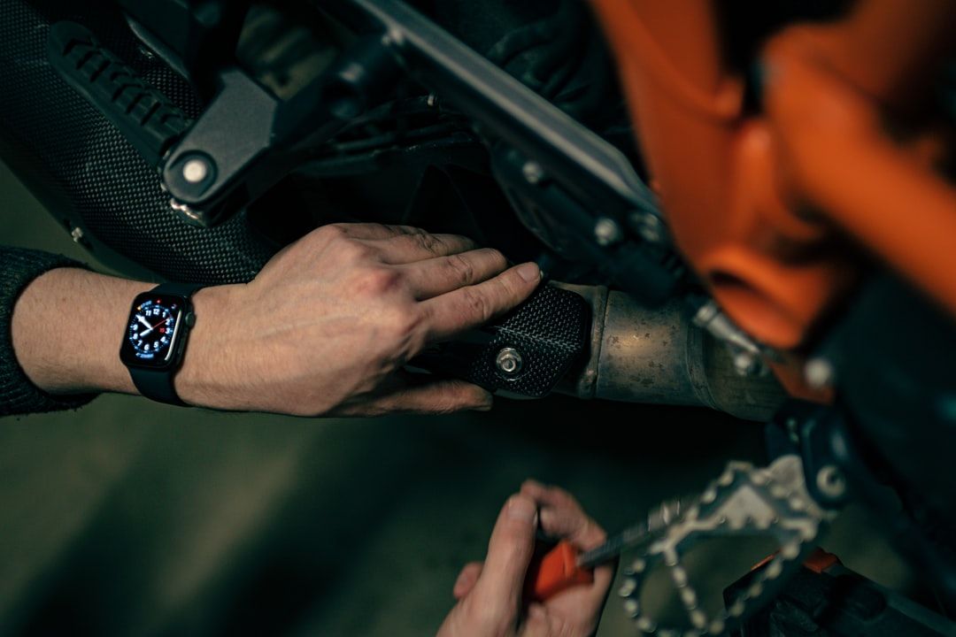 Hands handling a camouflaged firearm on an orange-clad person, close-up in low light