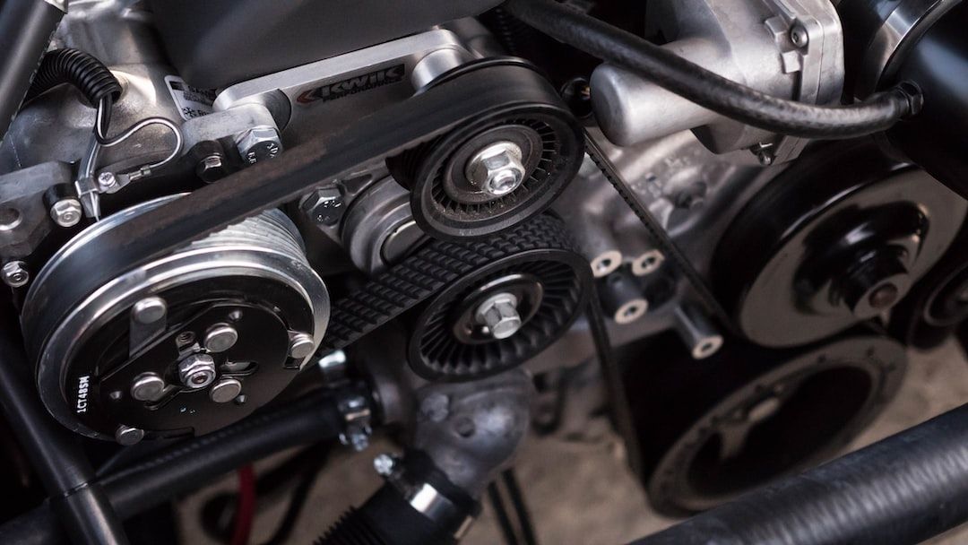 Close-up of a car engine with belts and pulleys, showing mechanical components.