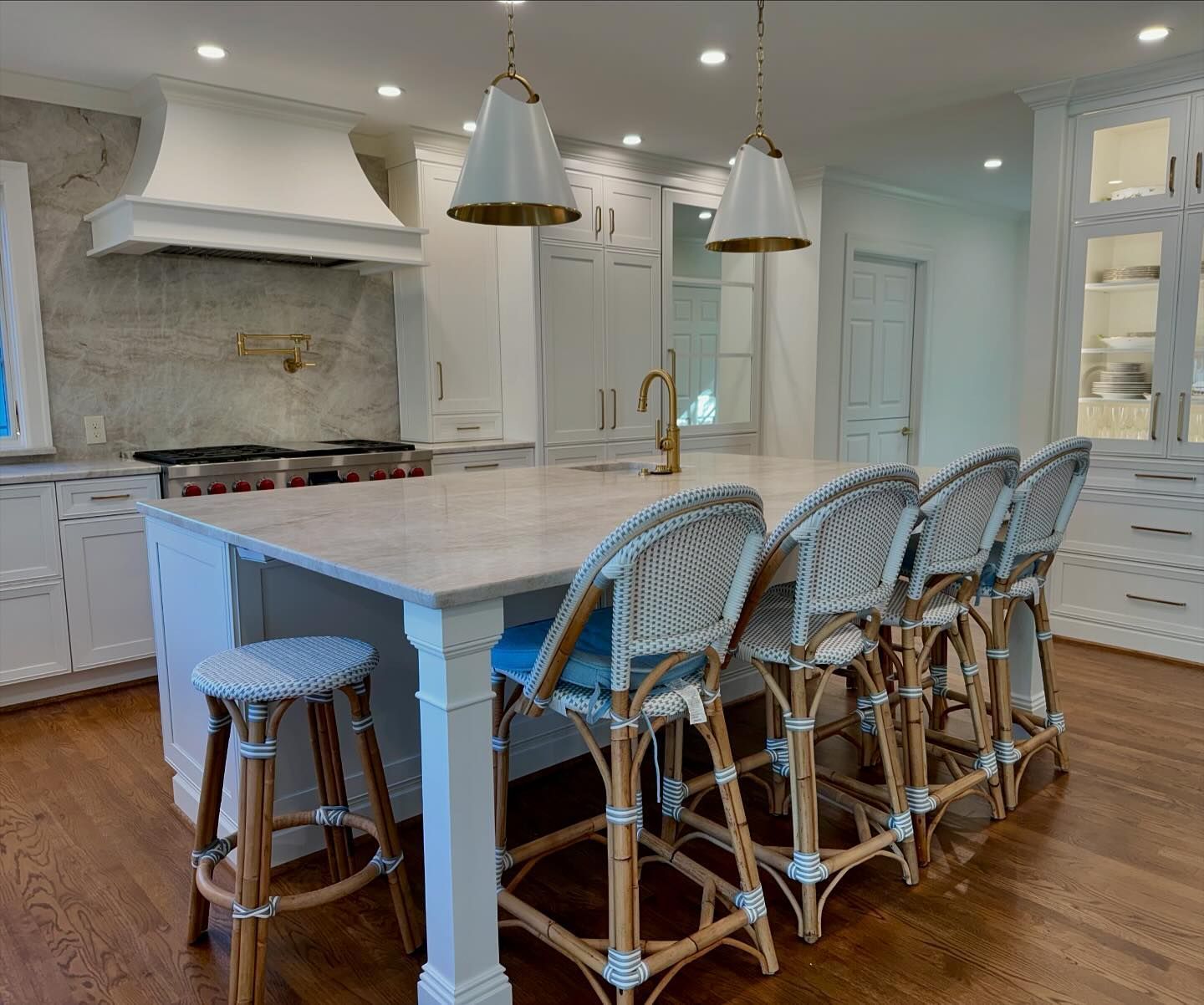 A kitchen with a large island and wicker chairs.