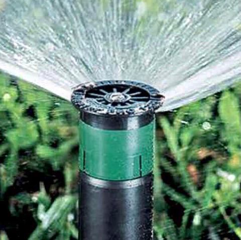 Black garden sprinkler spraying water in a green lawn