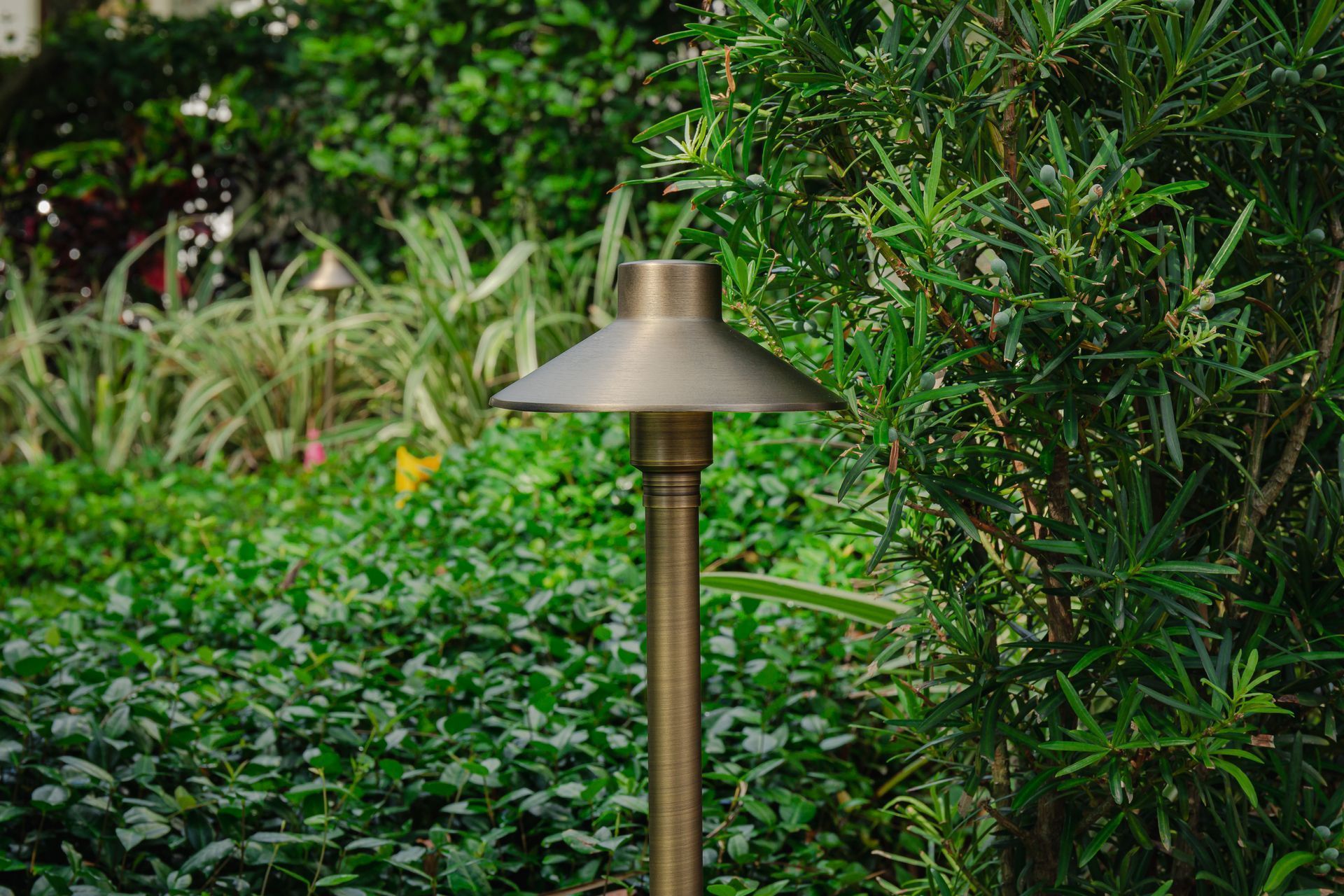 Copper garden lamp amid lush green shrubs and foliage
