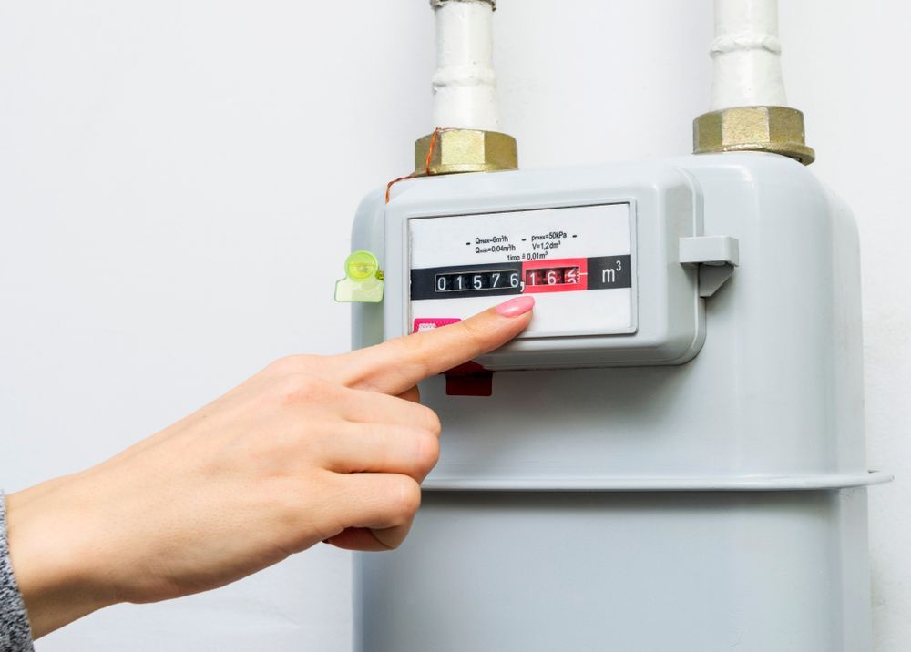 Hand Pressing a Red Button on A Gray Gas Meter with Pipes — NoDrip Plumbing & Roofing In Port Macquarie, NSW