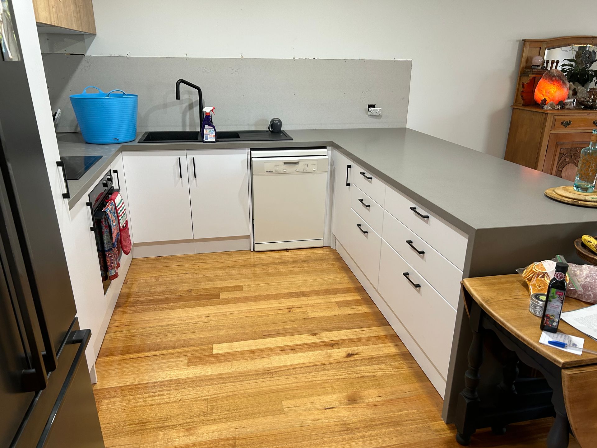 Modern kitchen with white cabinets, gray countertops, wood floor, and sink under a window