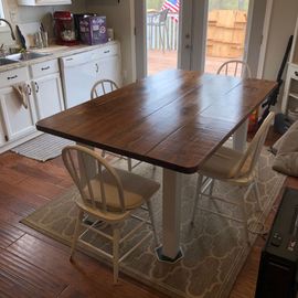 A kitchen with a wooden table and white chairs