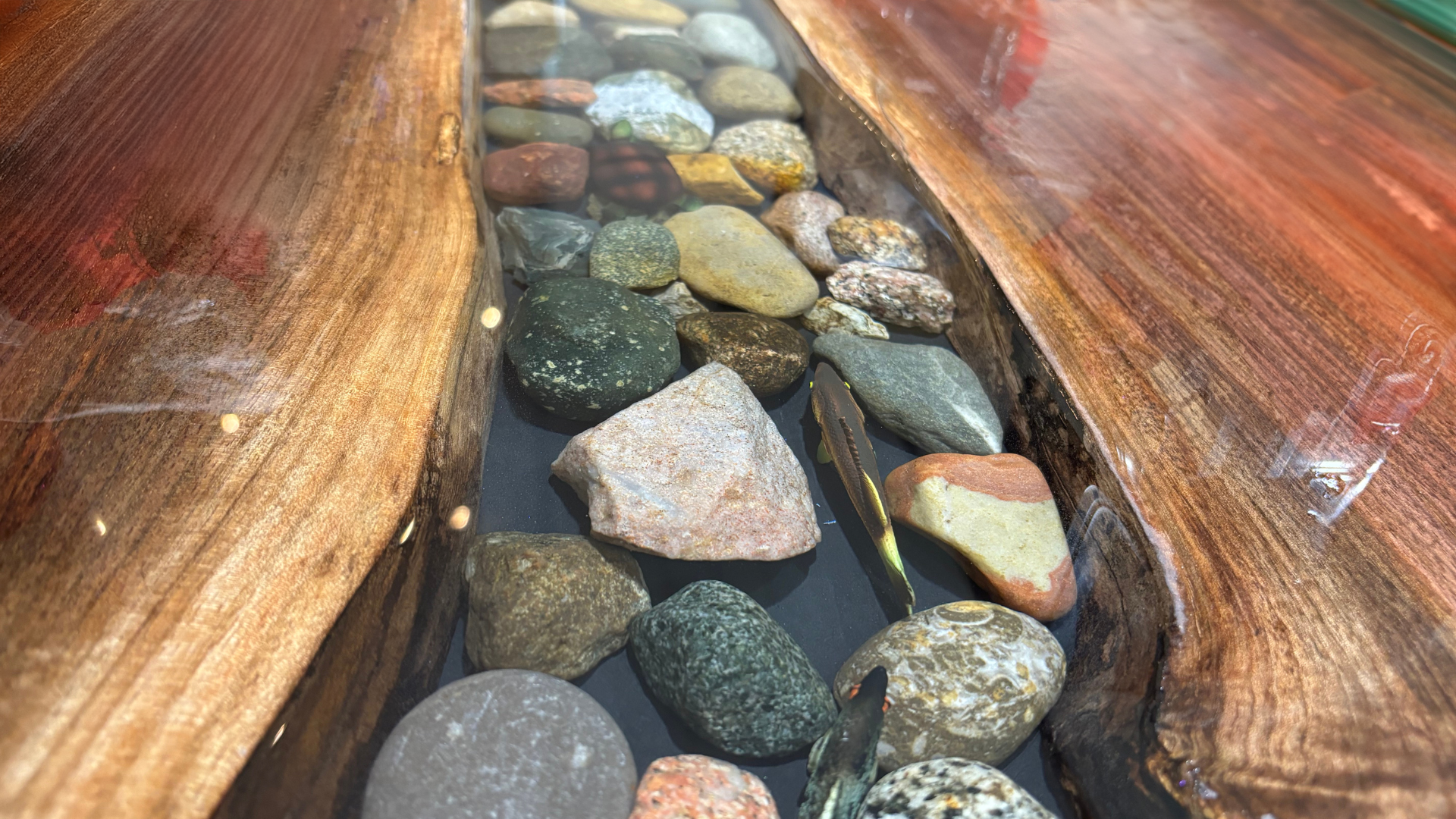 A wooden table with rocks in it that looks like a river.