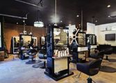 Hair salon interior with styling stations, mirrors, chairs, and brick accent wall.