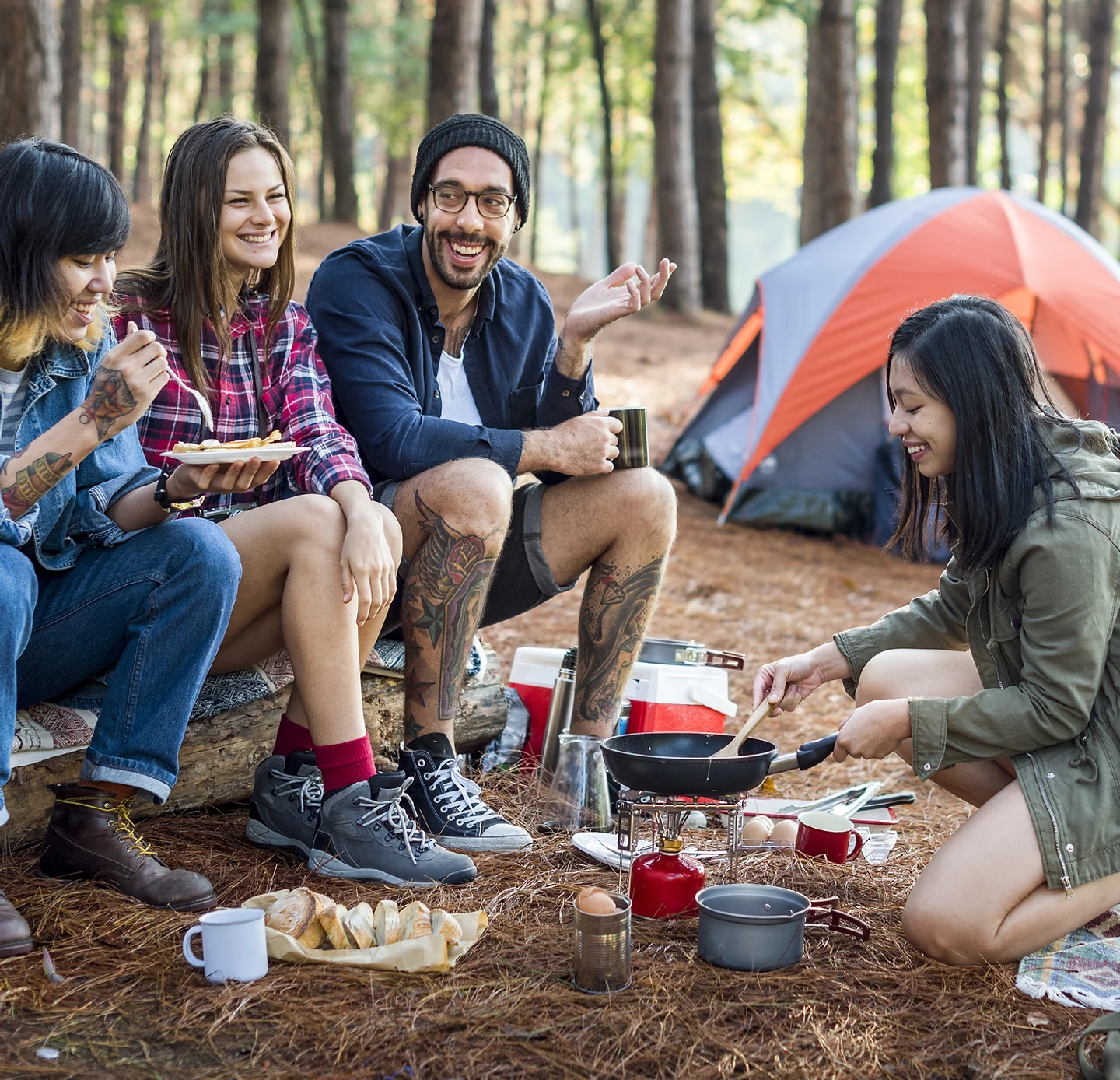 A group of people are sitting around a campfire in the woods.