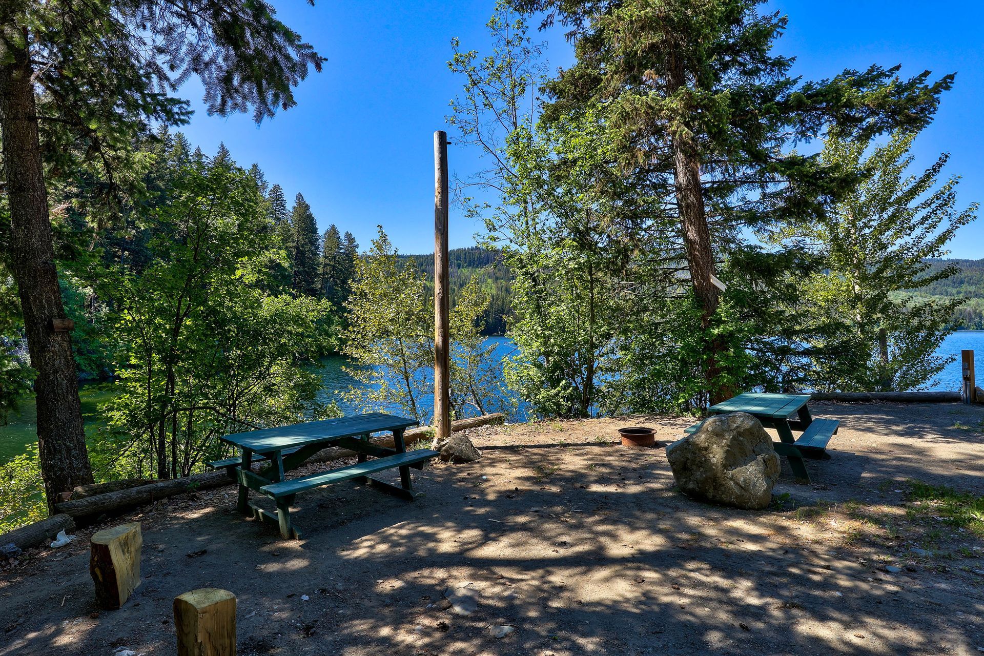 A picnic table with a view of a lake surrounded by trees