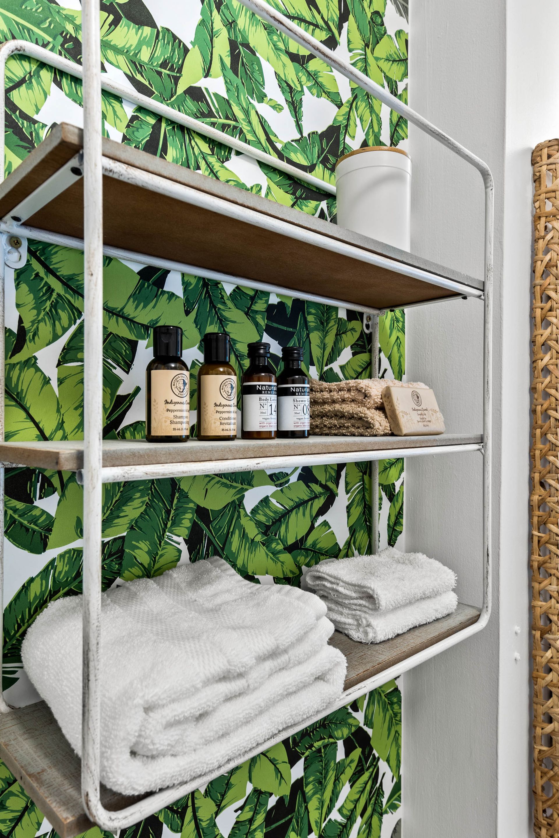 A bathroom with a shelf filled with towels and bottles.