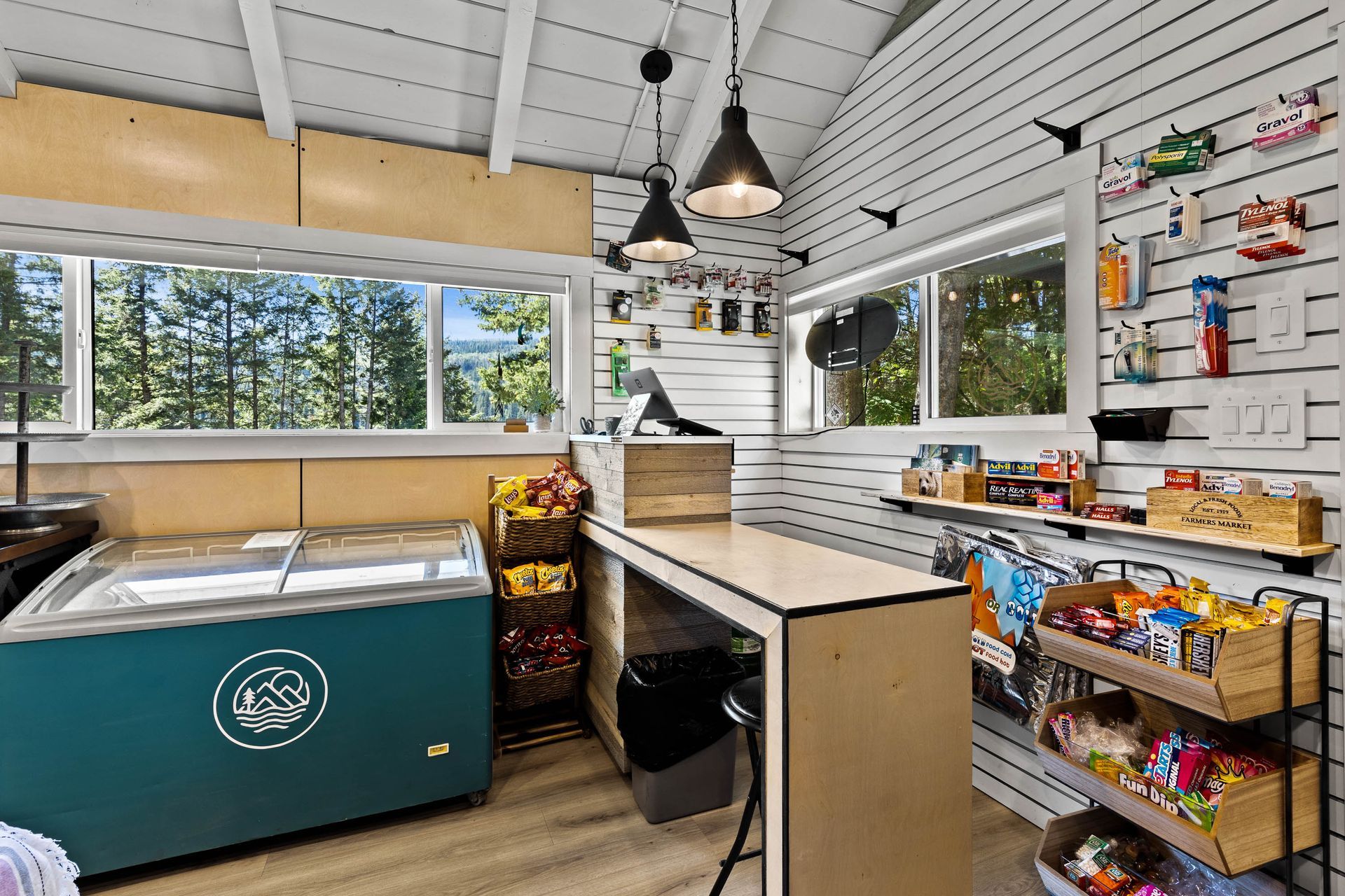 A room with a table , refrigerator , shelves and a window.