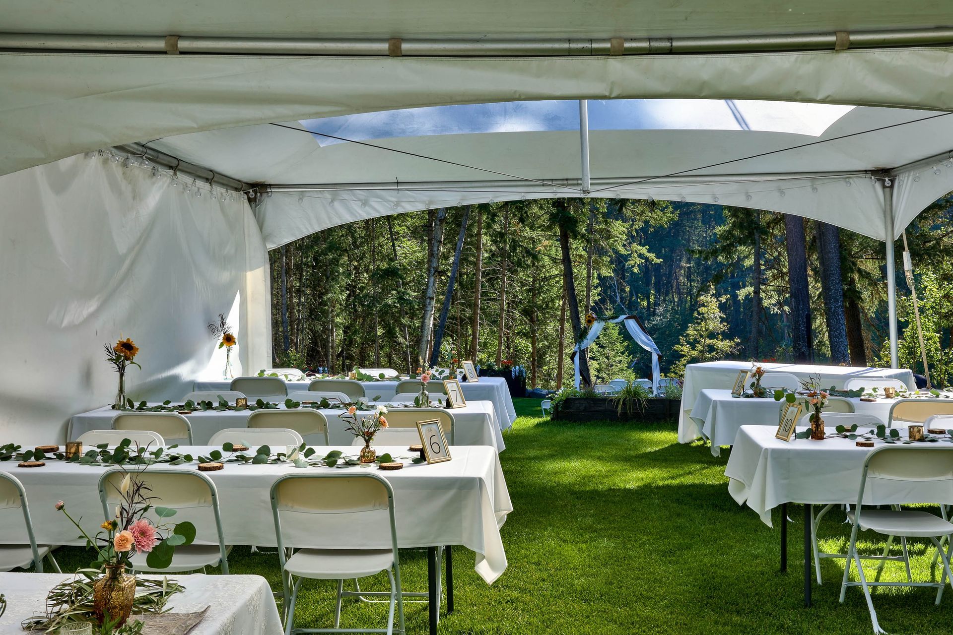 A tent with tables and chairs set up for a wedding reception.