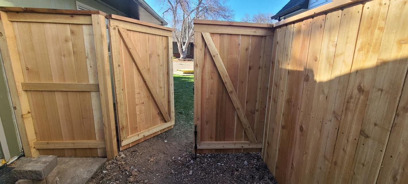Wooden fence with two open gates, leading to a yard.