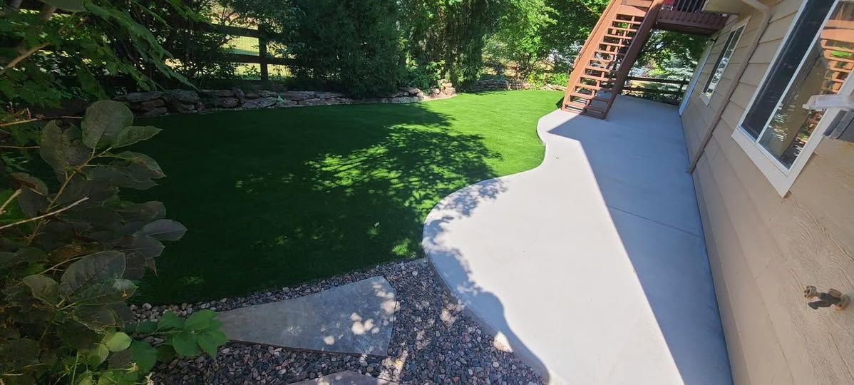 A backyard with green grass, a concrete patio, and a wooden deck.