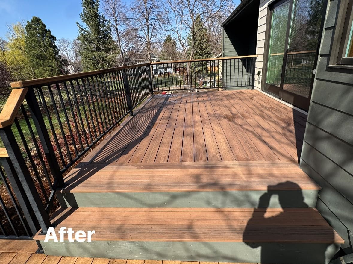 A newly stained wooden deck with black railings and steps on a sunny day.