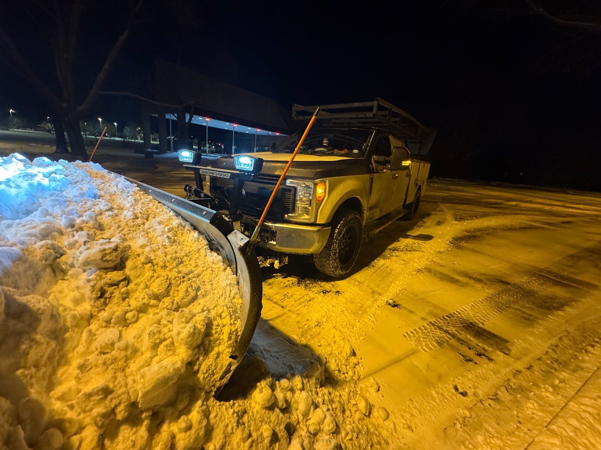 Yellow snowplow clearing snow at night.