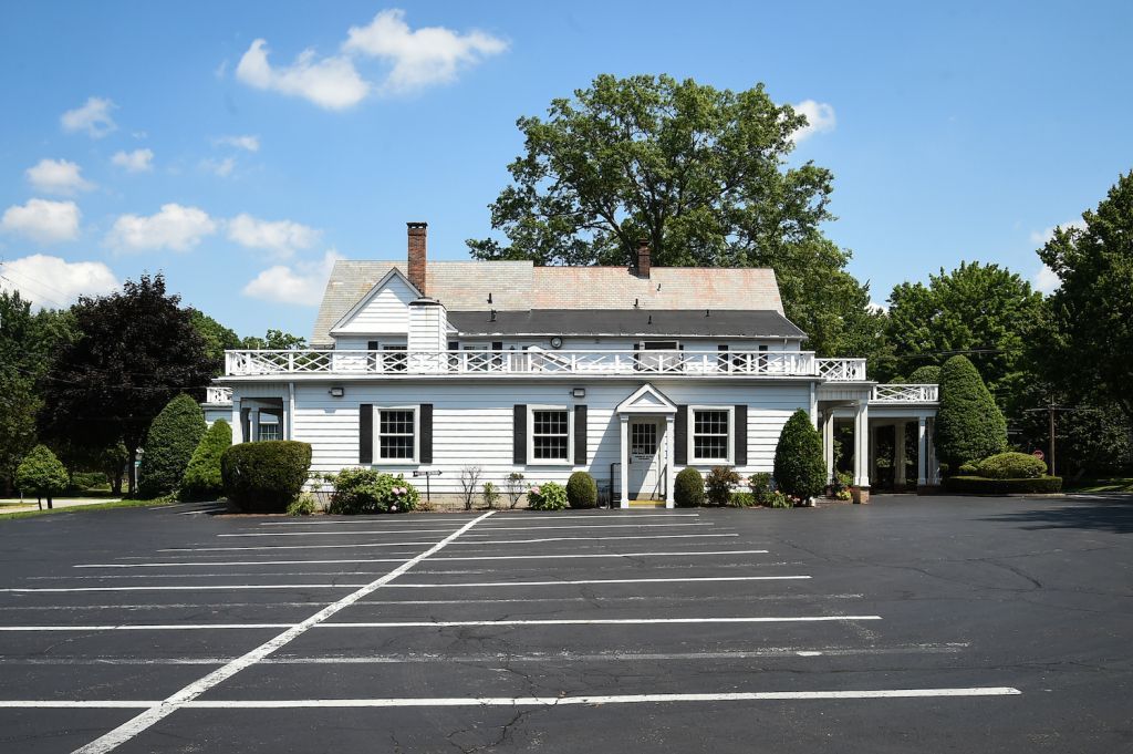 A large white house with a large parking lot in front of it