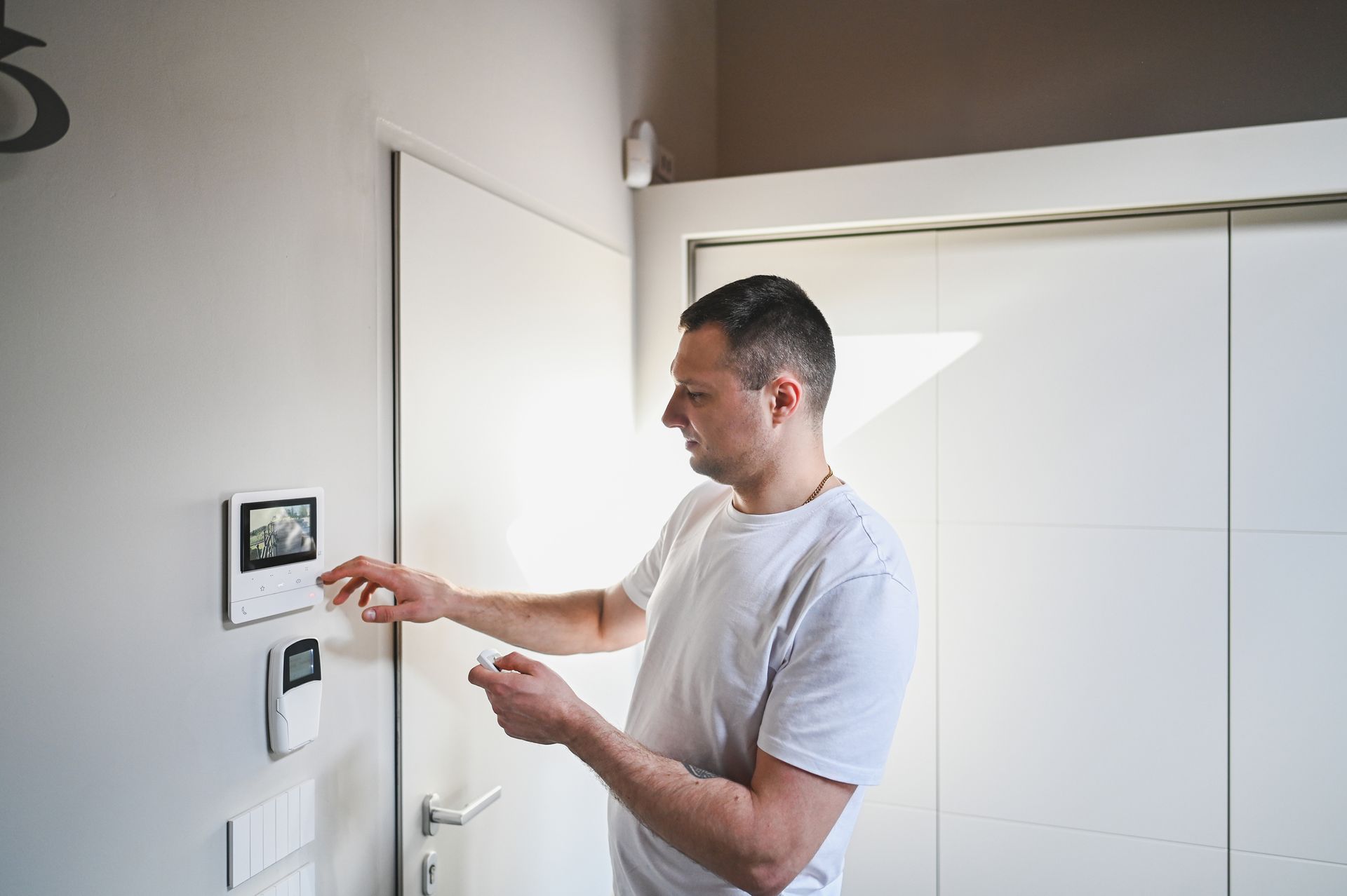 A man is checking the wall alarm, ensuring the alarm system is functioning properly and secure.