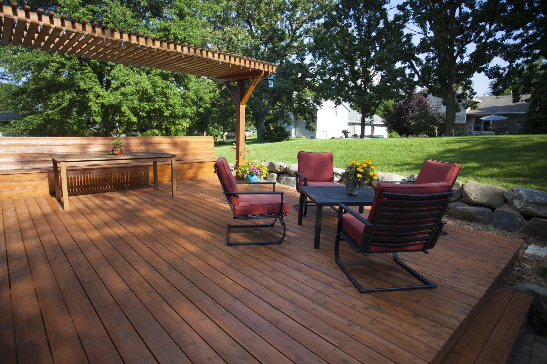 A wooden deck with chairs and a table under a pergola