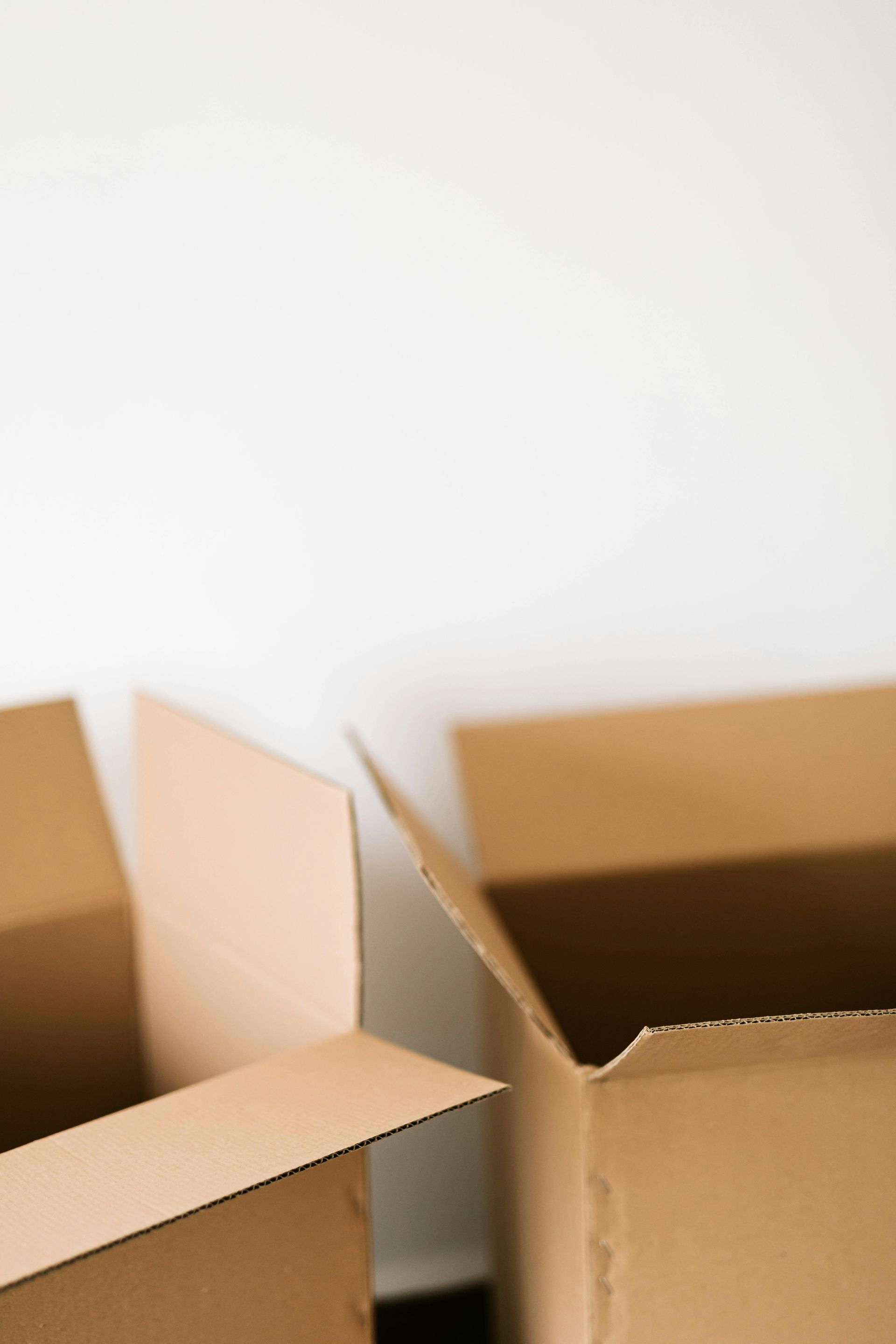 Two open cardboard moving boxes against a white wall.