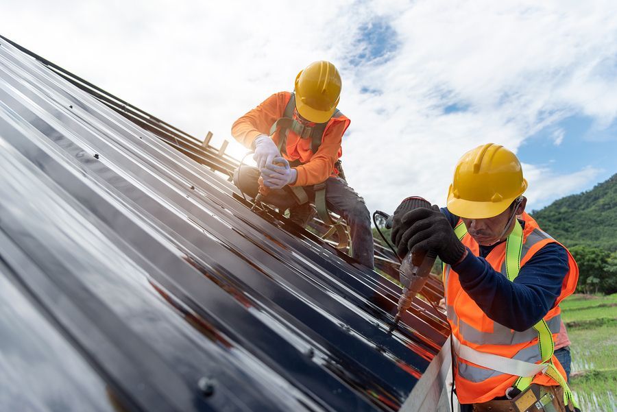 two individuals work on a roof safe with contractors insurance coverage