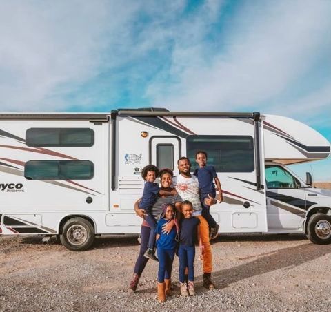 family smiles in front of their RV knowing it is protected by recreational insurance