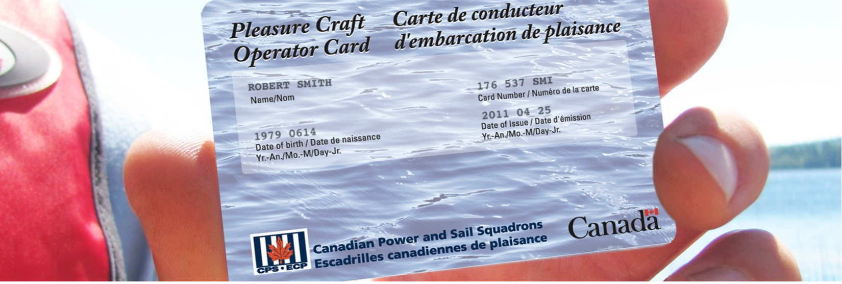 Person holding a Pleasure Craft Operator Card; the card has text in French and English with a Canadian logo.