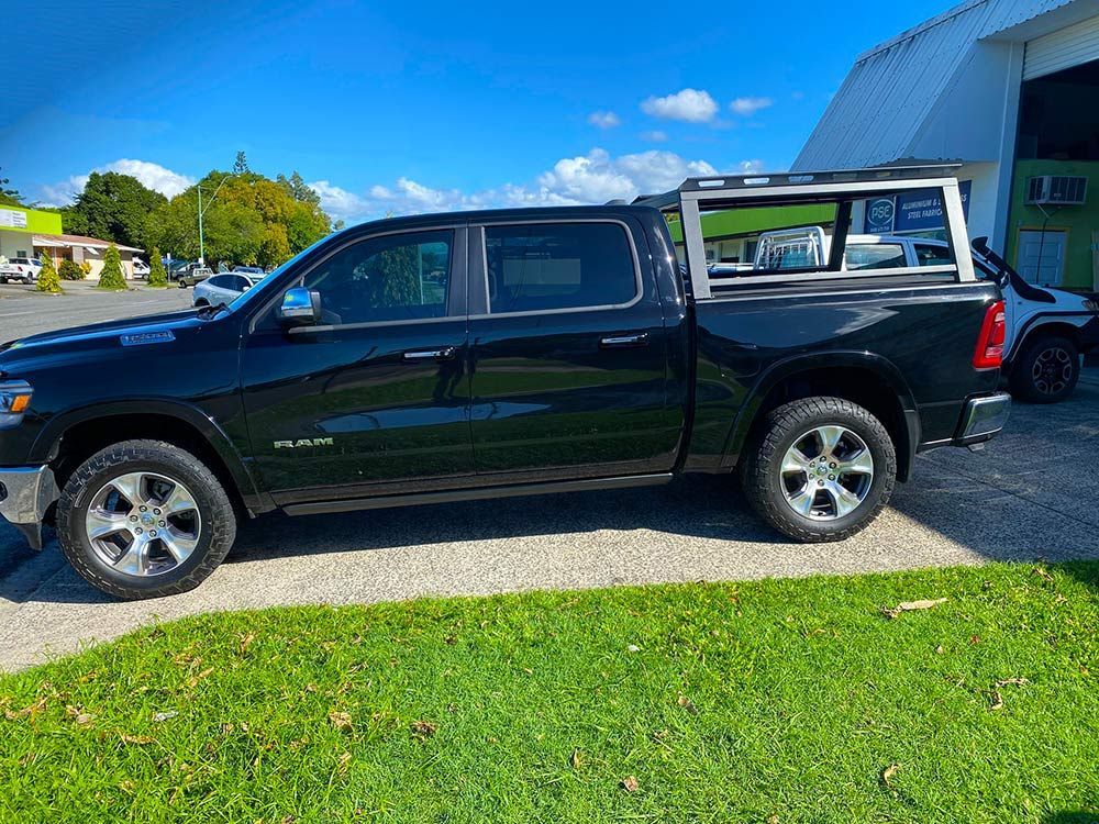 A black dodge ram truck is parked in a driveway next to a building — PSE Stainless Steel Fabrications in Manunda, QLD