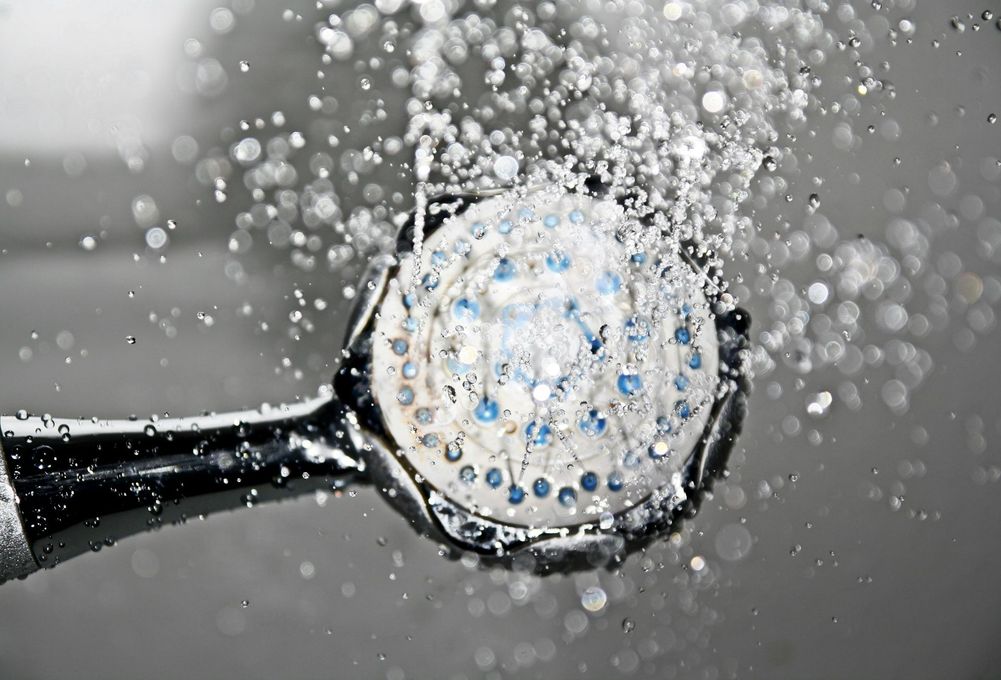 Shower head spraying water, droplets in motion, close-up shot.