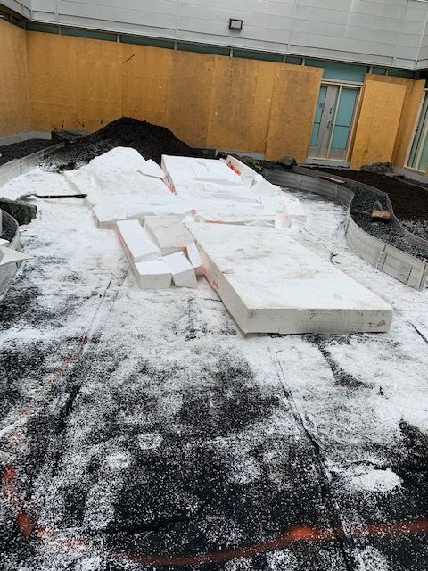 Panneaux d'isolation en mousse blanche éparpillés sur une surface noire. Débris et mur jaune en arrière-plan.