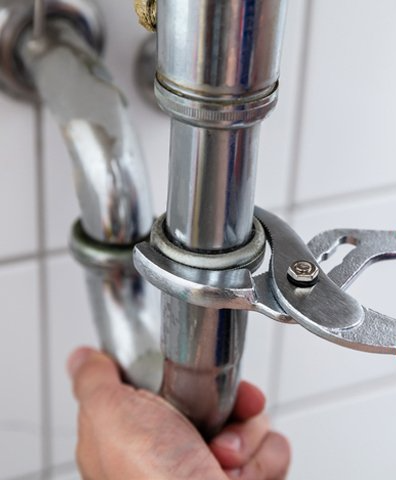 Plumber Repairing Sink With Adjustable Wrench
